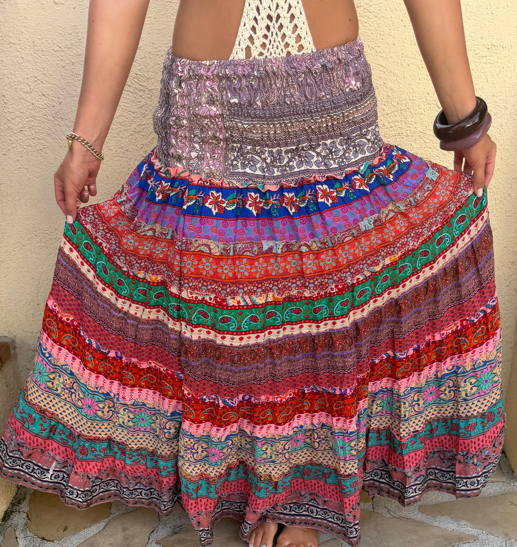 Person wearing a colorful patterned hippie layered skirt on a stone pavement.