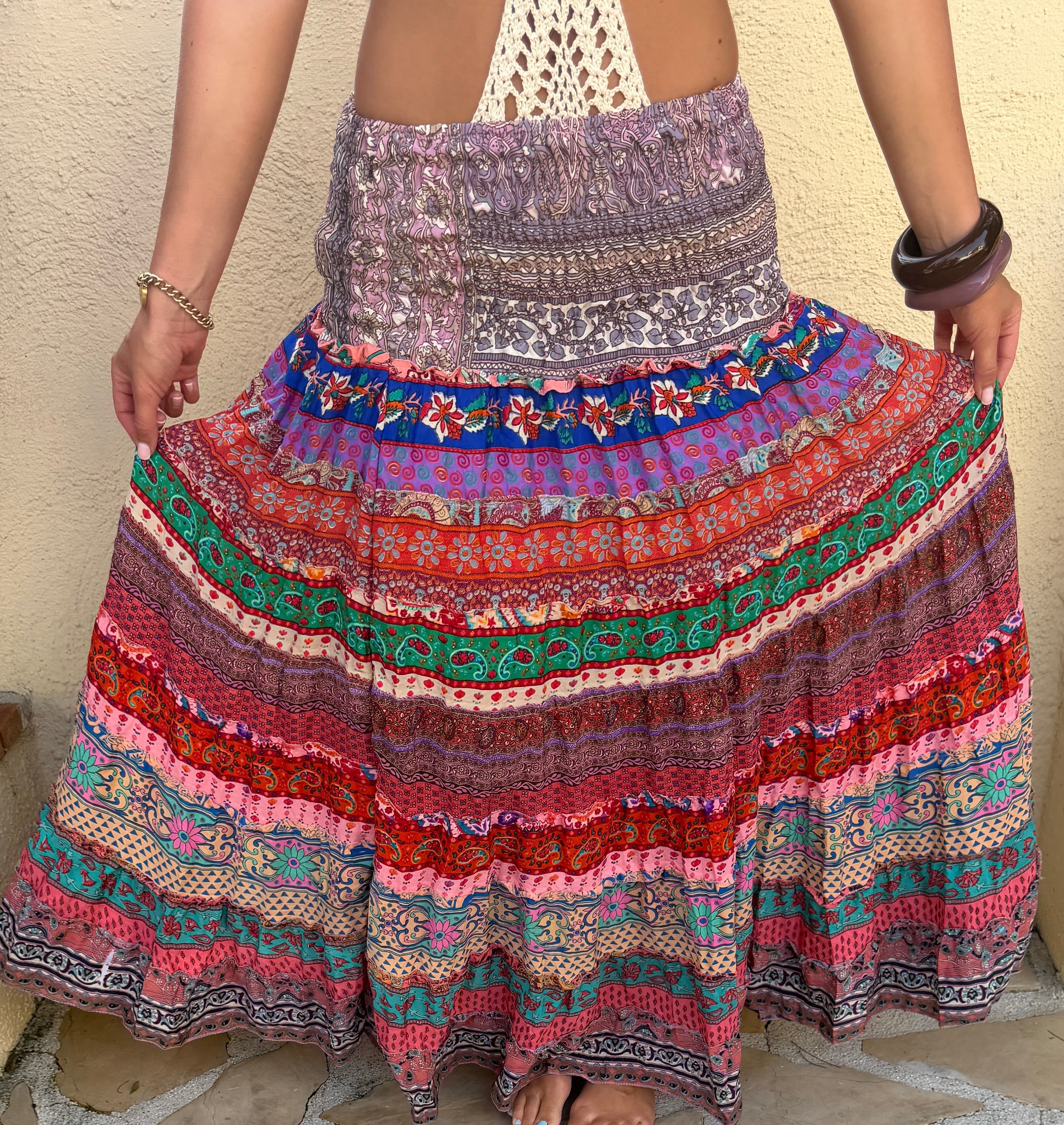 Person wearing a colorful patterned hippie layered skirt on a stone pavement.